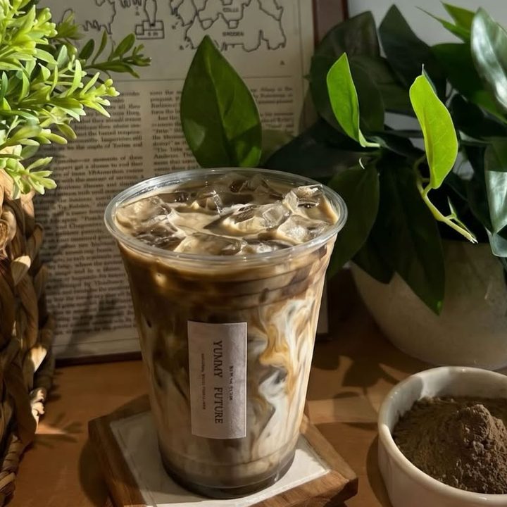 Iced hojicha latte next to a bowl of hojicha powder