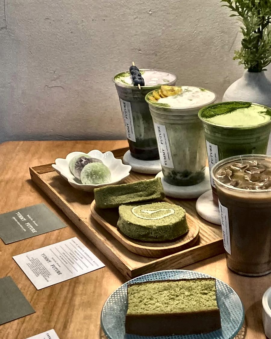 Matcha drinks, matcha roll cake and mochi on a wooden tray